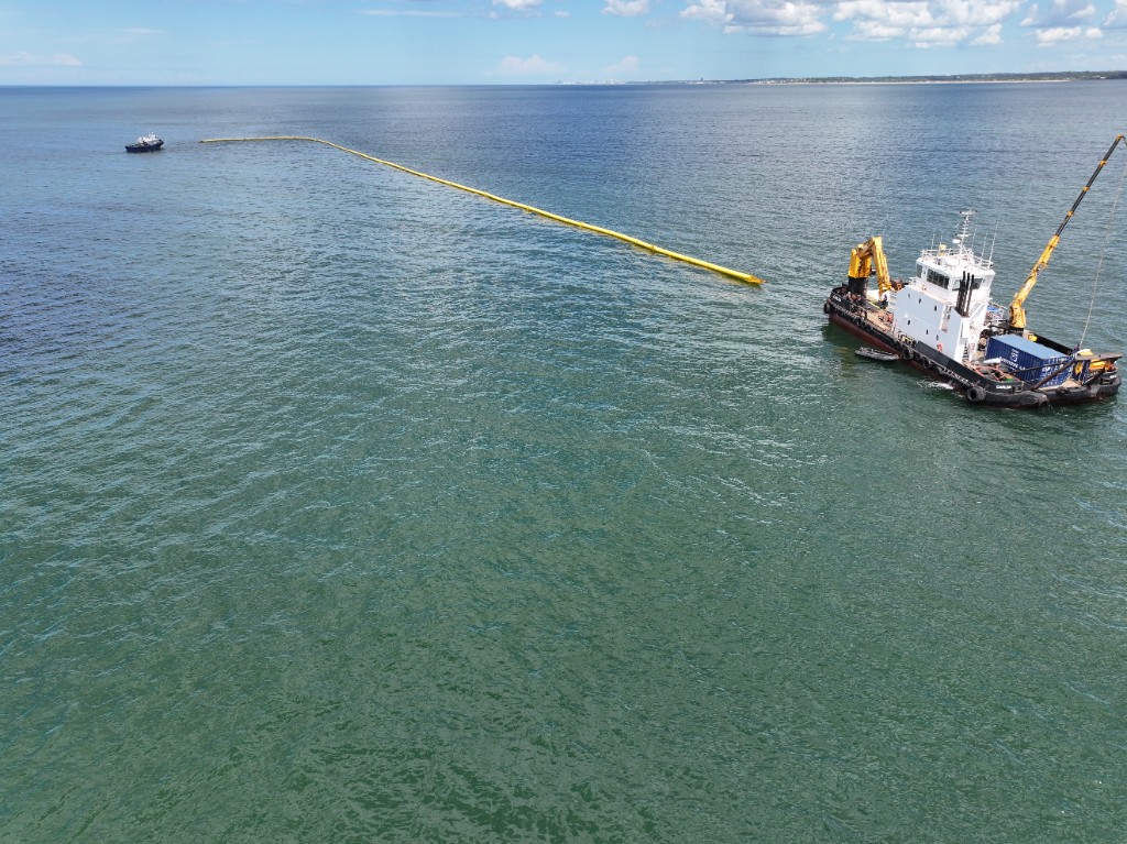 Línea de contención marítima con embarcaciones de apoyo